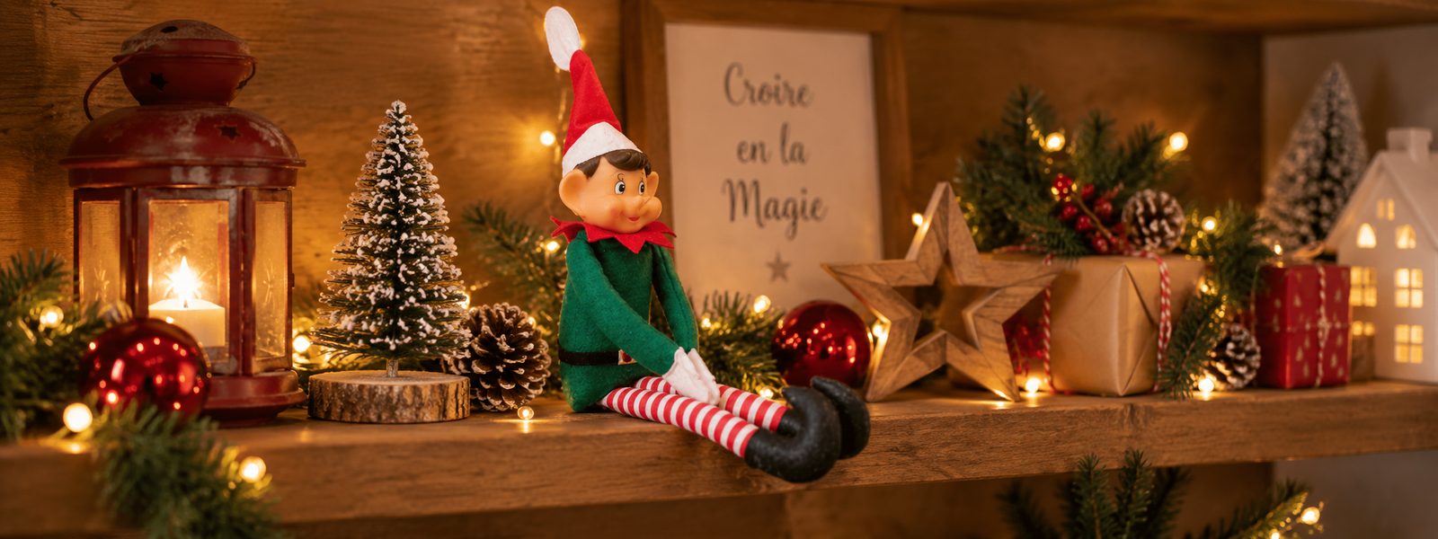 Lutin farceur assis sur une étagère de Noël éclairée par des guirlandes