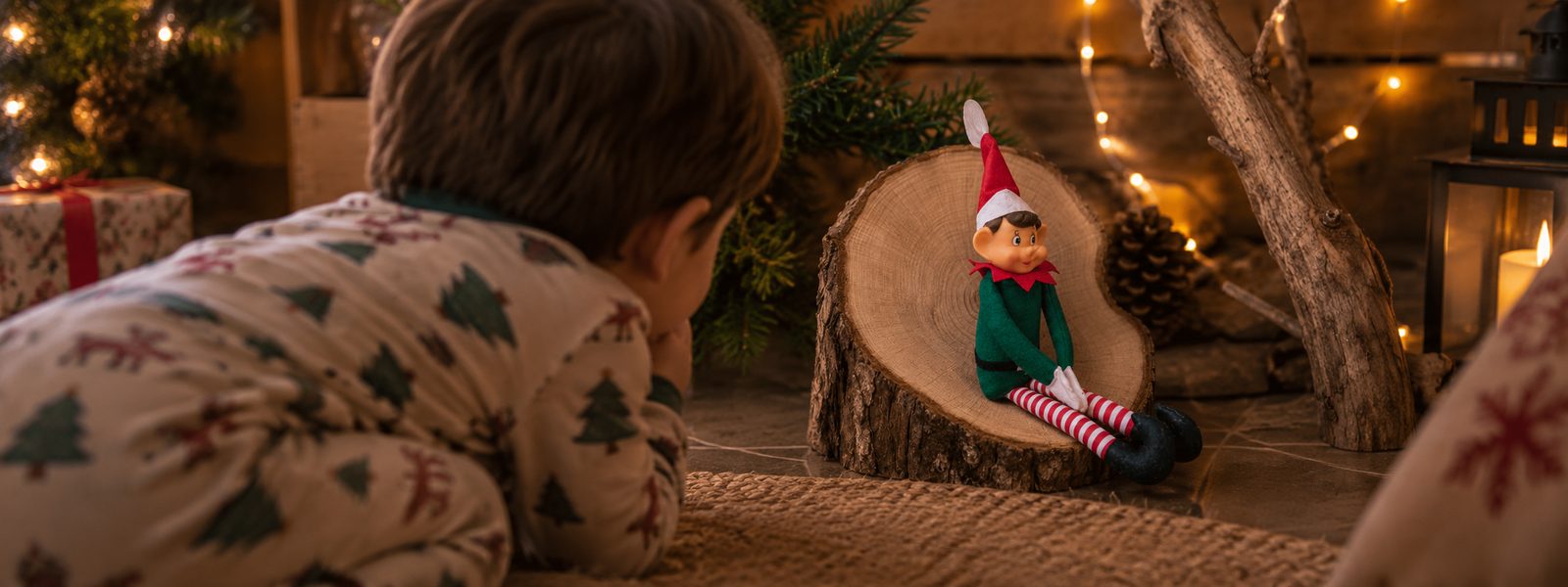 Enfant en pyjama allongé face à son lutin farceur posé sur une rondelle de bois